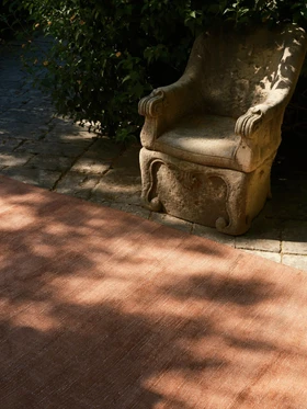 Vara rug in Clay, outdoor editorial detail beside a stone garden chair