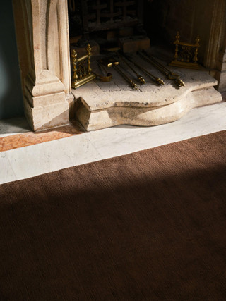 Mohair Sheared rug in Carob, corner detail beside a fireplace