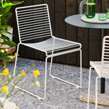 Two HAY Hee Outdoor Dining Chairs next to a table on a patio
