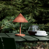 Mater Terra Portable Lamp in Coffee Rust Red on an outdoor table Mater Terra Portable Lamp in Coffee Rust Red on an outdoor table