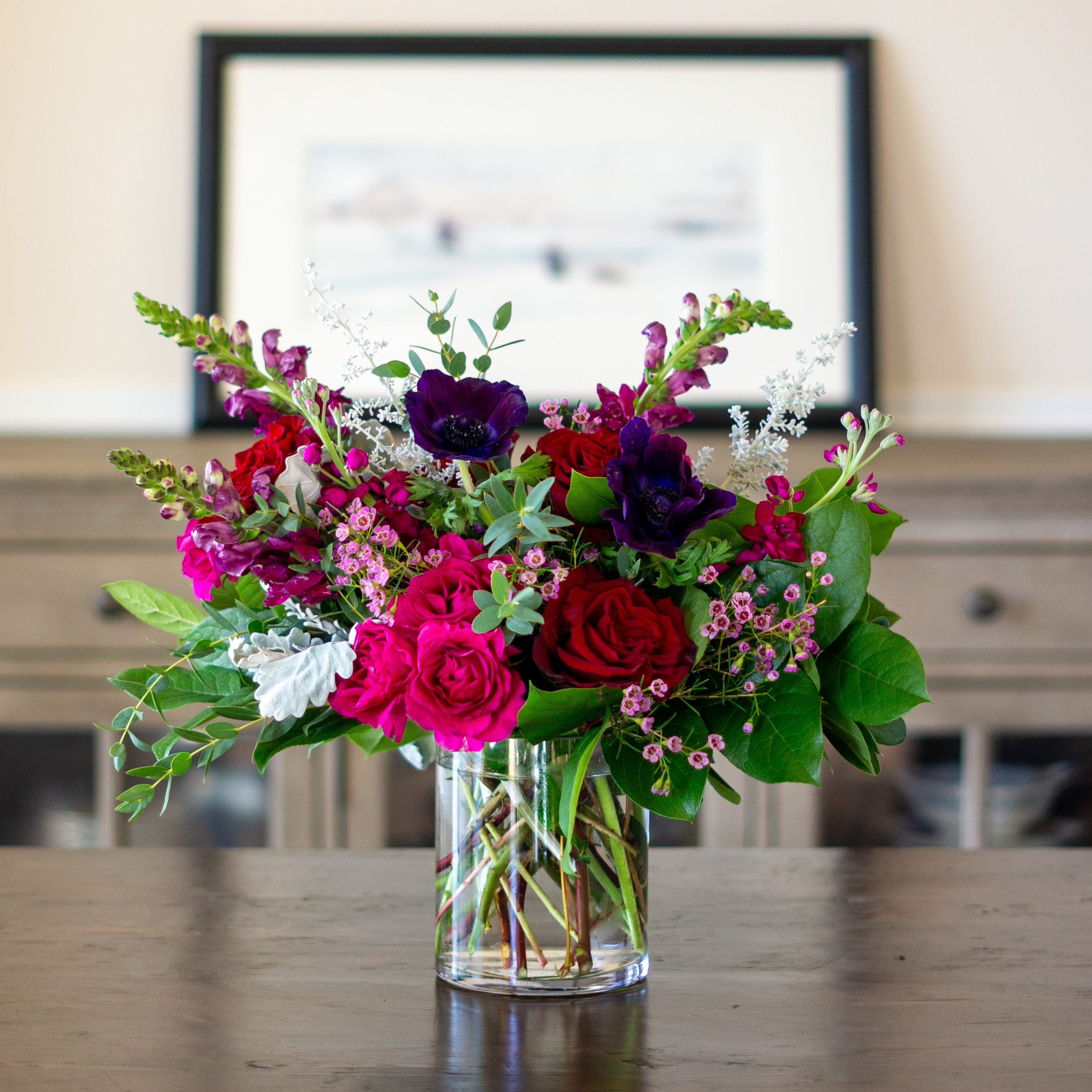 A singe clear glass urn with a dozen pink, red, and white roses with greenery for Valentine's Day delivery to Charlotte NC.