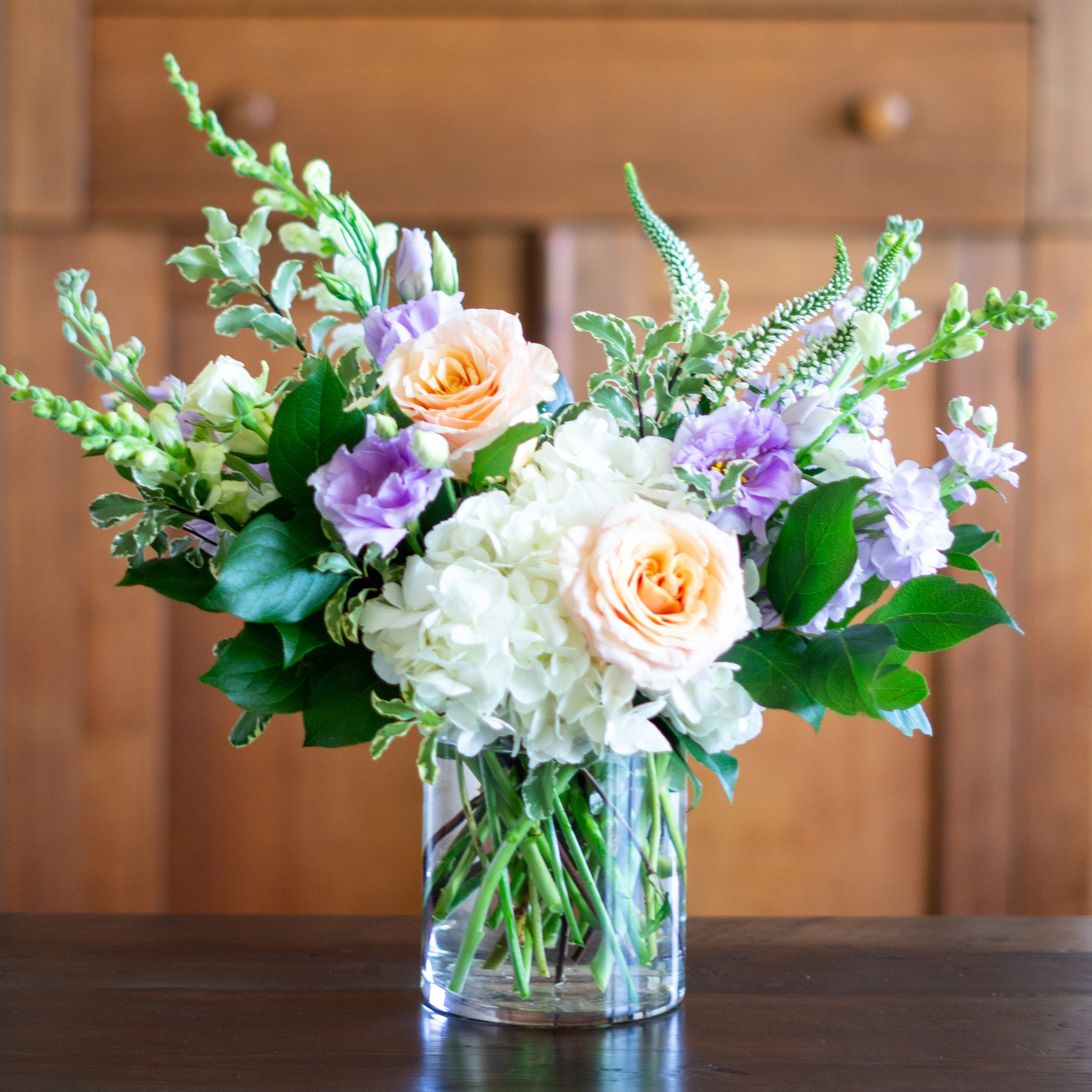 Peach valentines day flower arrangement for delivery to Charlotte NC. Image is a closeup of a pink rose with a peach center surrounded by peach stock and pink majolika spray roses. 