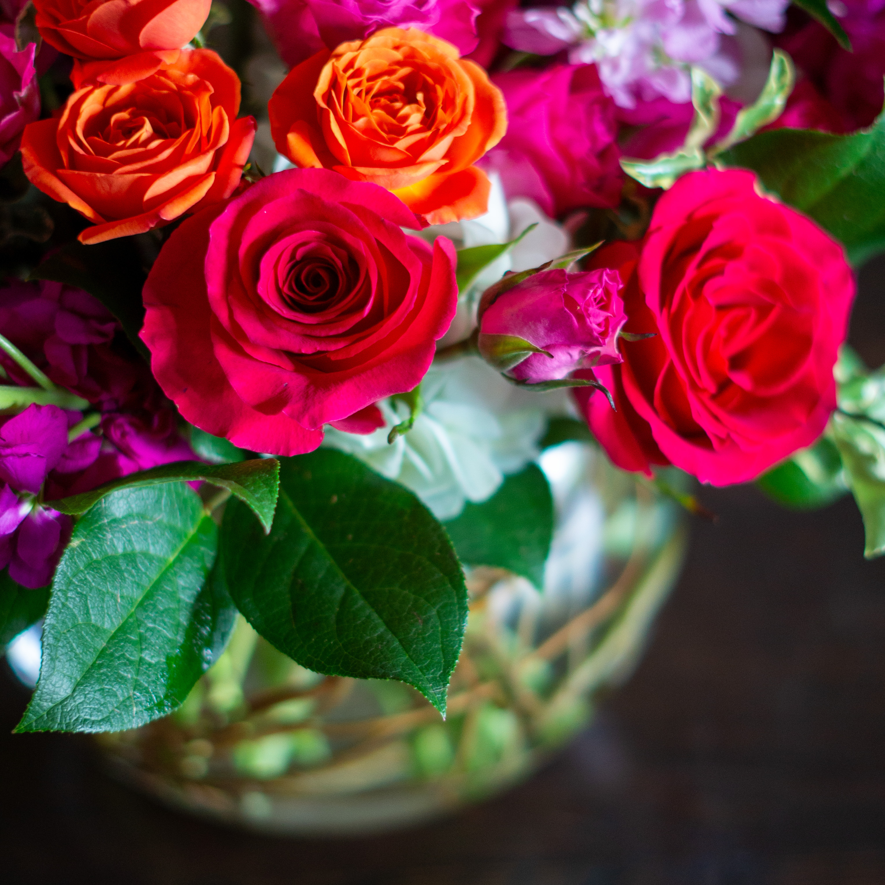 Peach valentines day flowers on a blue tablecloth. Flowers include peach roses, cream lisianthus, peach stock, white hydrangea, pink spray roses, and pink hypericum berries accented with eucalyptus. 