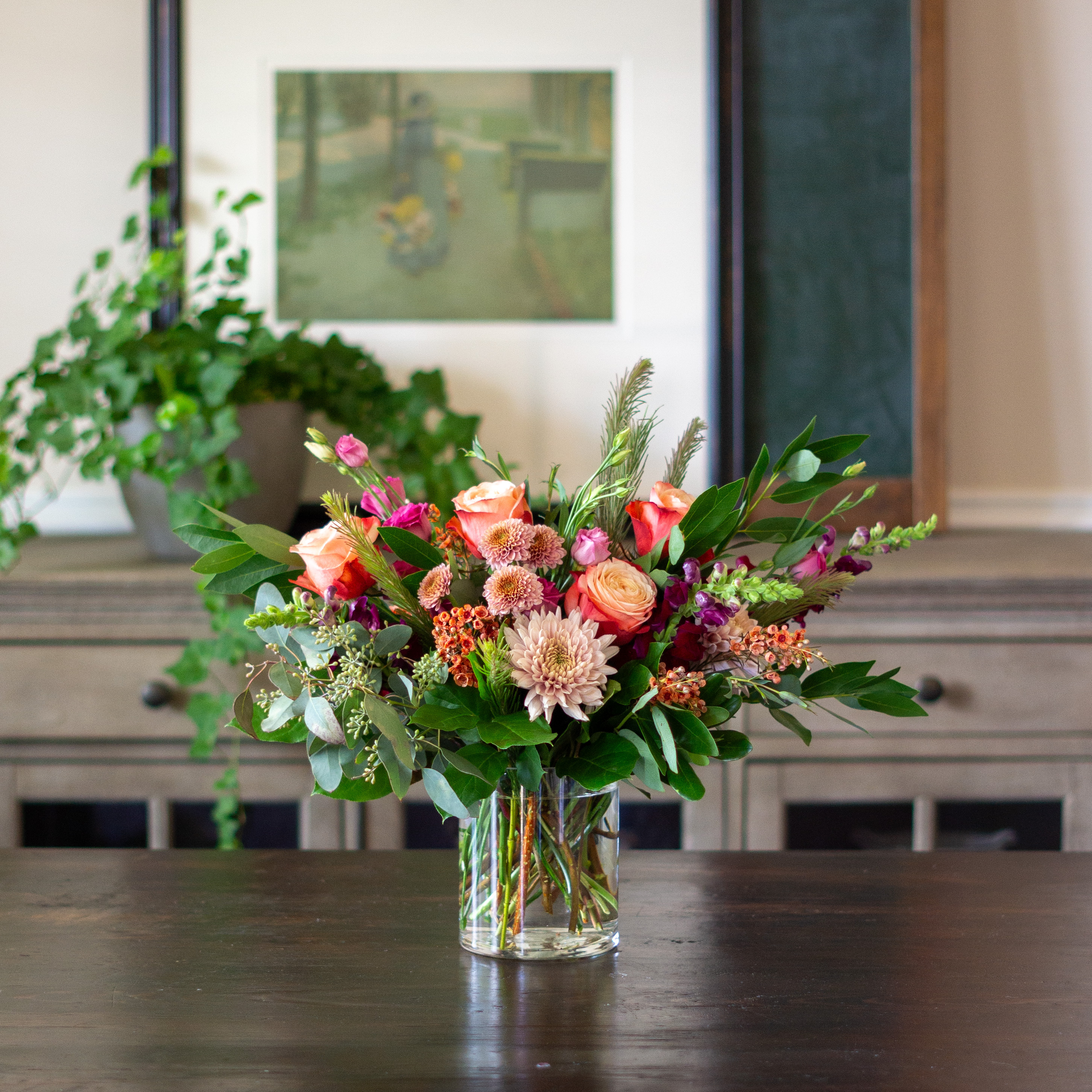 Peach valentines day flowers on a blue tablecloth. Flowers include peach roses, cream lisianthus, peach stock, white hydrangea, pink spray roses, and pink hypericum berries accented with eucalyptus. 