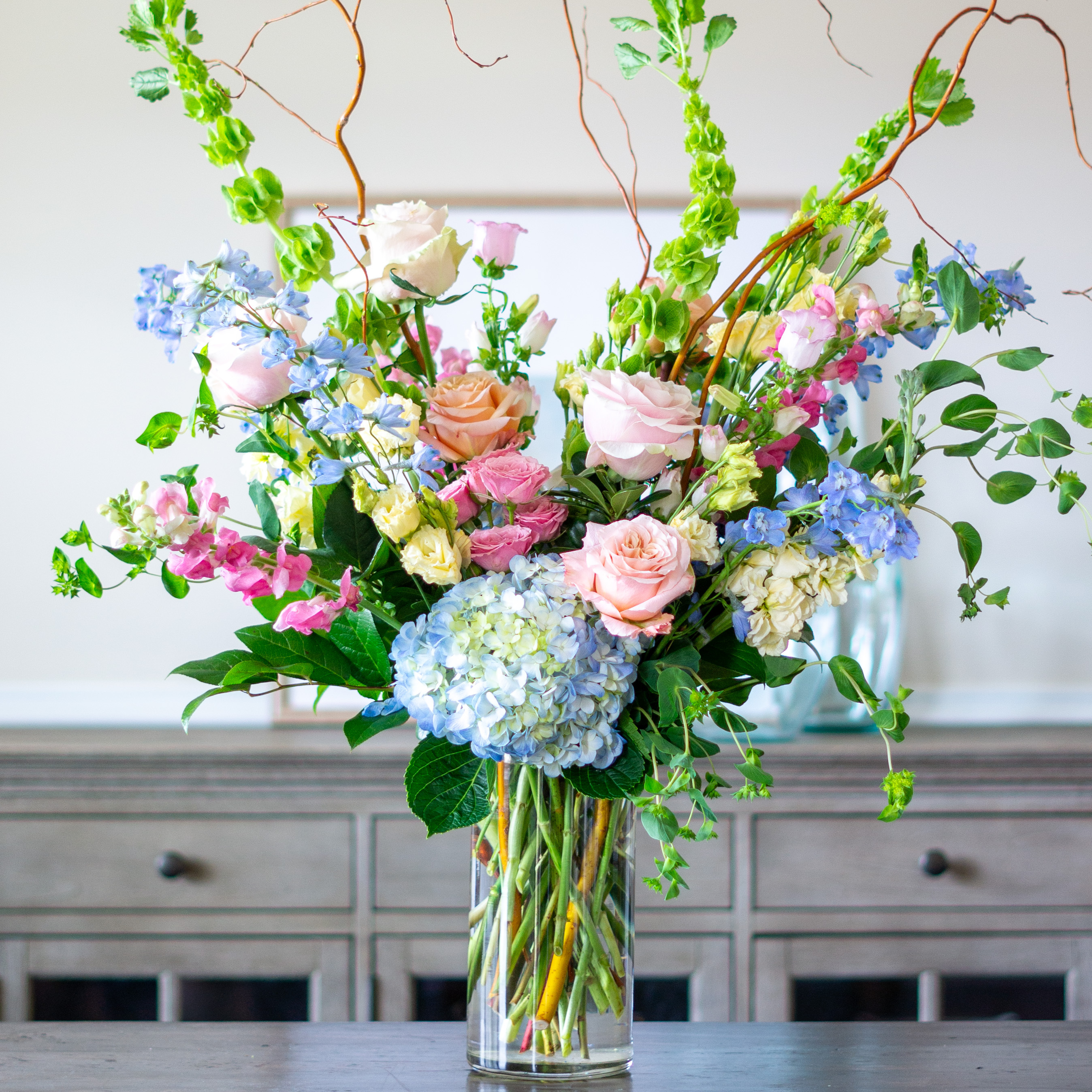 Large Valentines Day flowers for delivery to Charlotte, NC. Image shows a large garden style arrangement of peach roses, peach stock, white hydrangea, cream lisianthus, pink hypericum berries, and pink spray roses accented with spiral eucalyptus and gunni. 