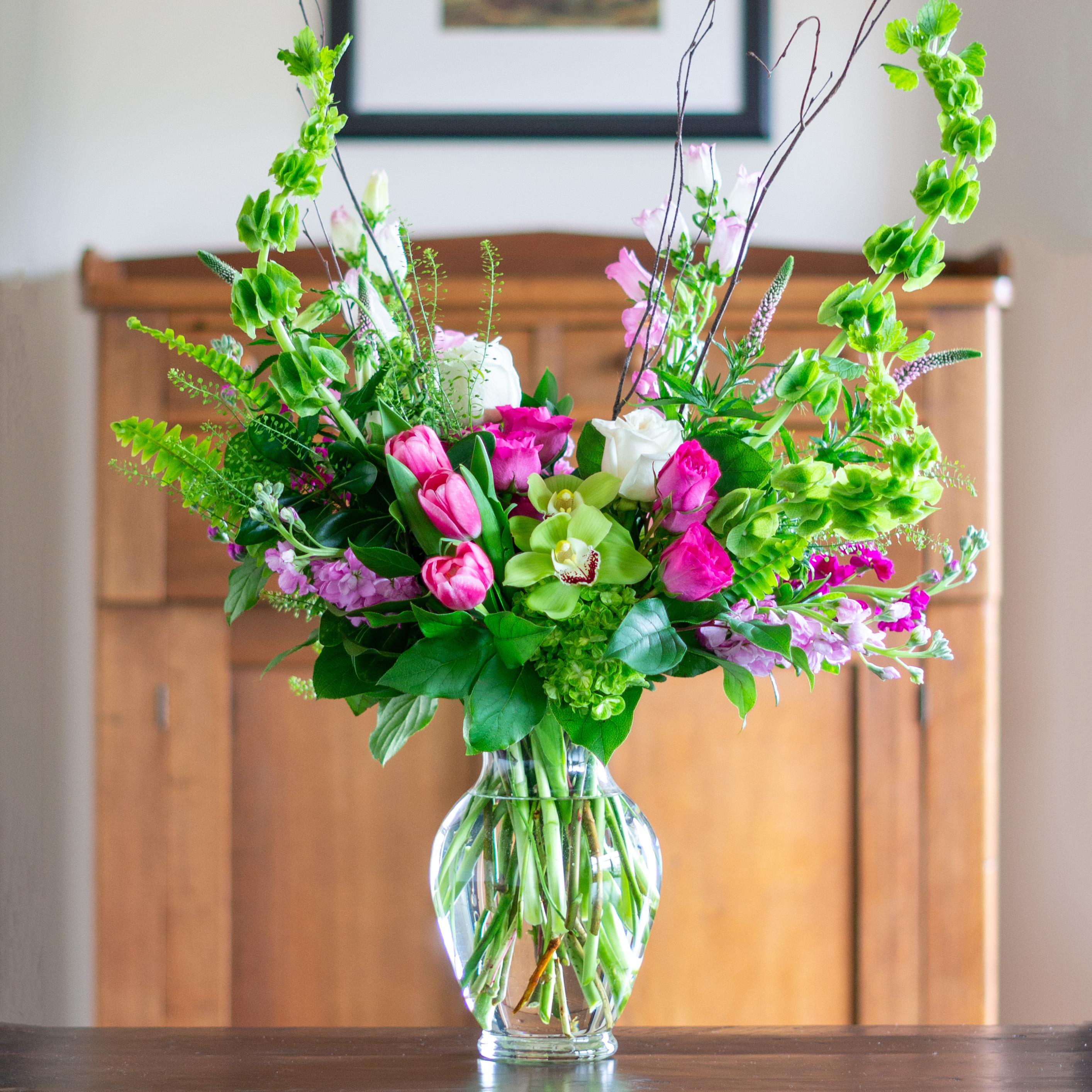 Peach valentines day flowers on a blue tablecloth. Flowers include peach roses, cream lisianthus, peach stock, white hydrangea, pink spray roses, and pink hypericum berries accented with eucalyptus. 