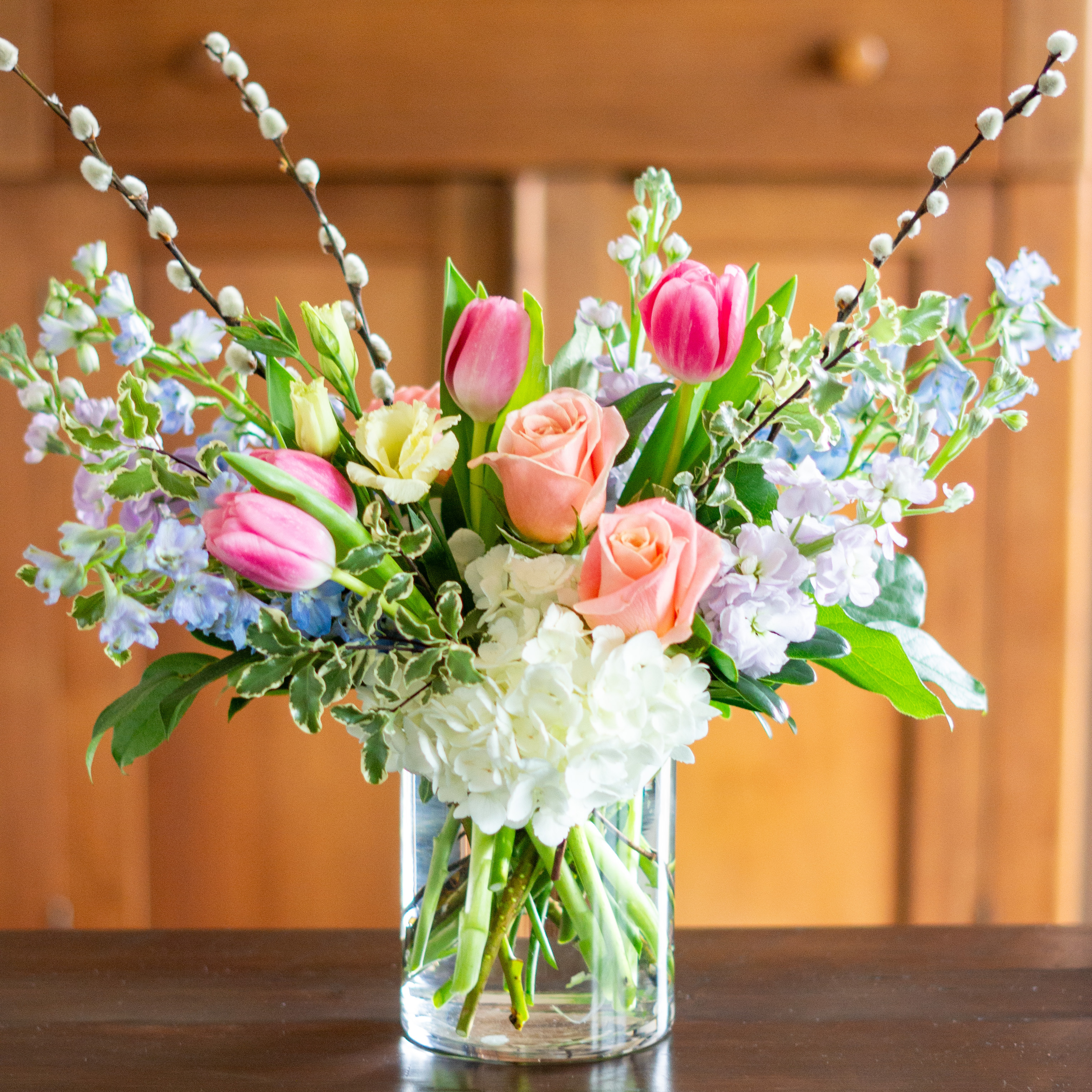 Top down view of a Nightingale's valentine's day roses - image shows a perfect three dozen red roses arranged in a Charlotte vase and sitting on a black table with a white background.  