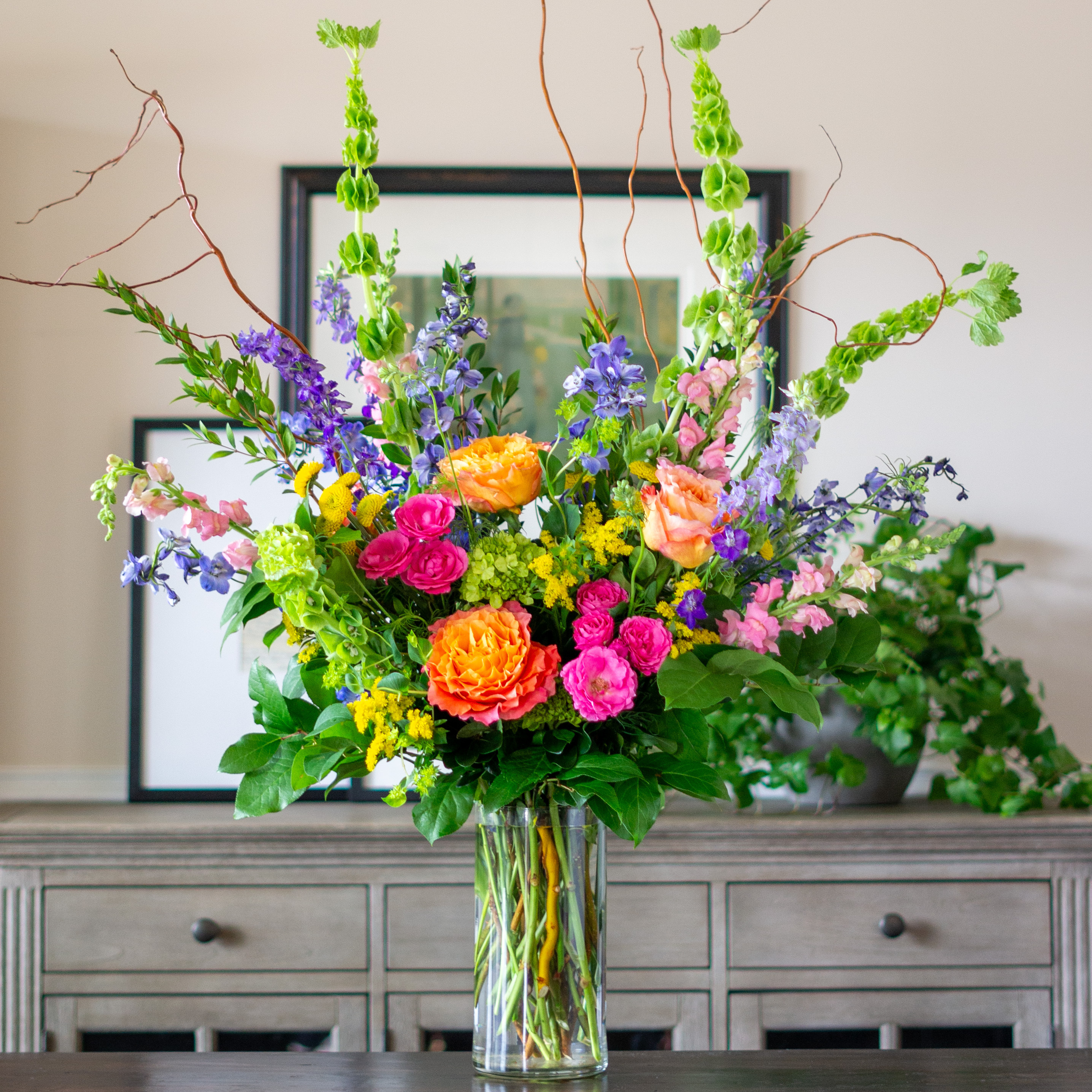 A singe clear glass urn with a dozen pink, red, and white roses with greenery for Valentine's Day delivery to Charlotte NC.