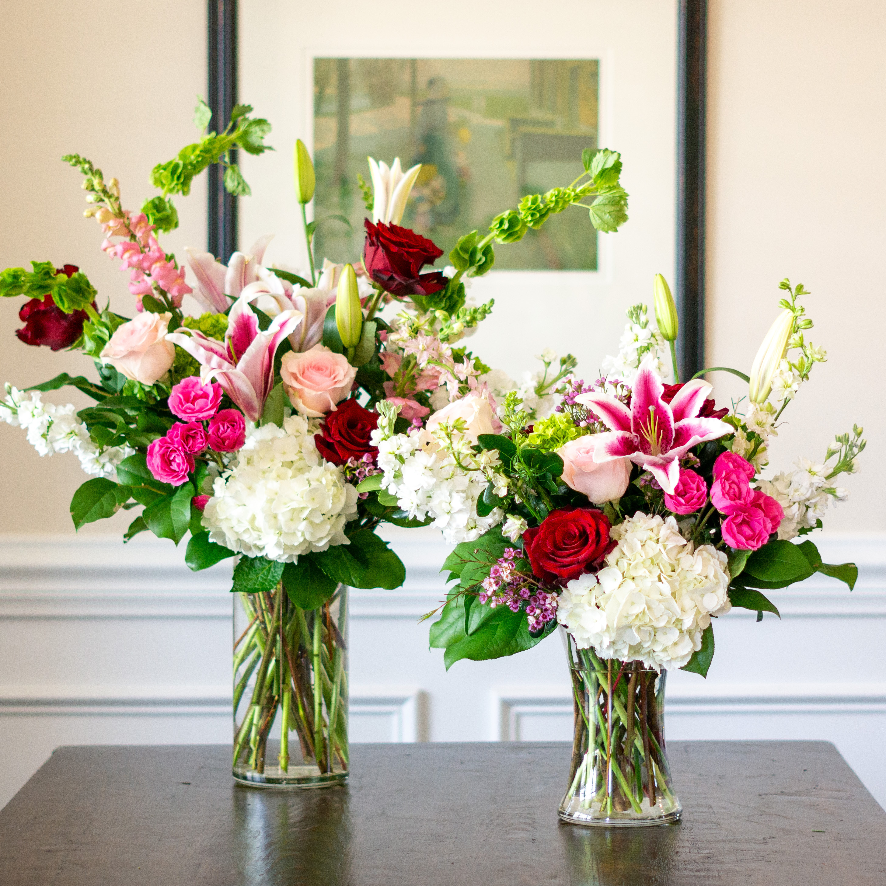 Top down view of a Nightingale's valentine's day roses - image shows a perfect three dozen red roses arranged in a Charlotte vase and sitting on a black table with a white background.  
