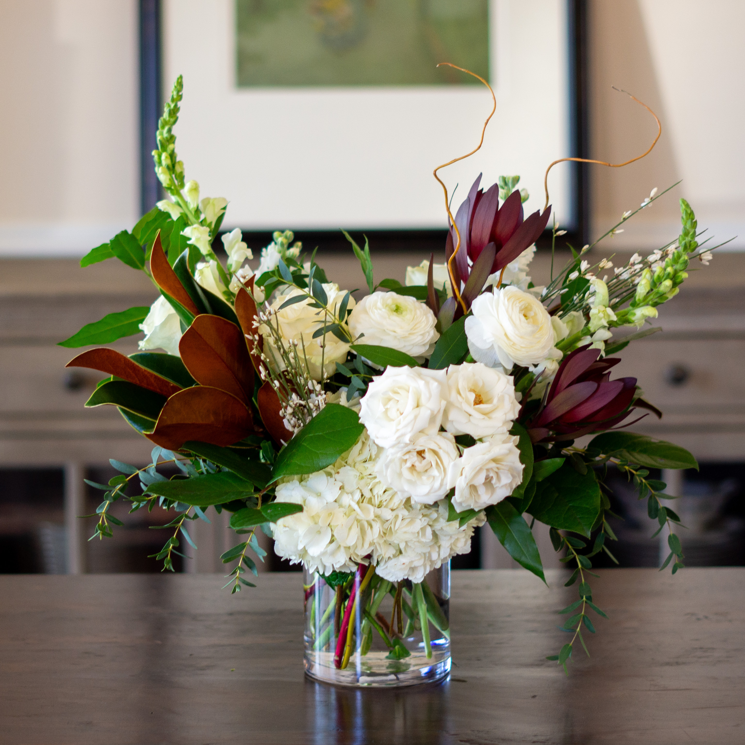 A singe clear glass urn with a dozen pink, red, and white roses with greenery for Valentine's Day delivery to Charlotte NC.