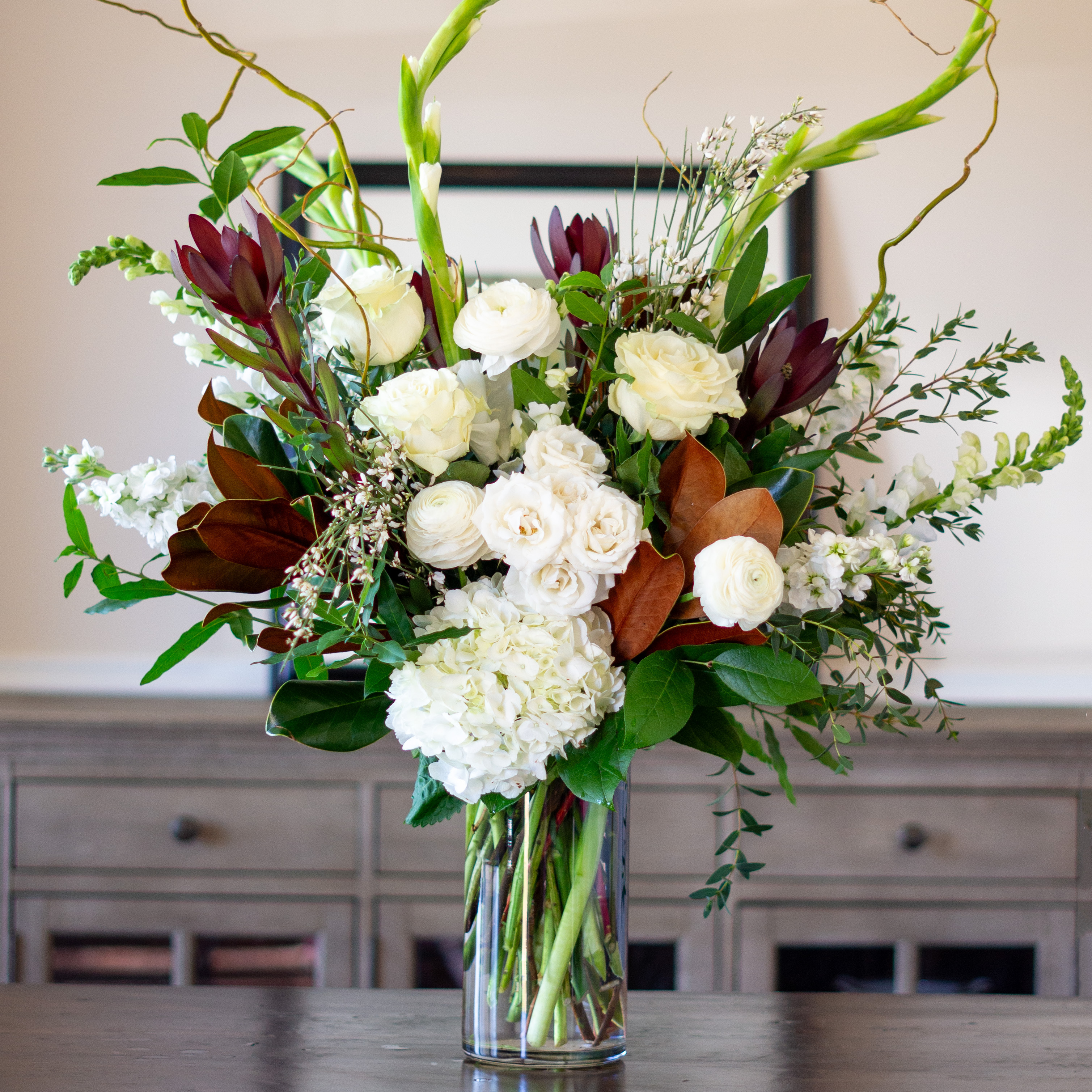 Top down view of a Nightingale's valentine's day roses - image shows a perfect three dozen red roses arranged in a Charlotte vase and sitting on a black table with a white background.  