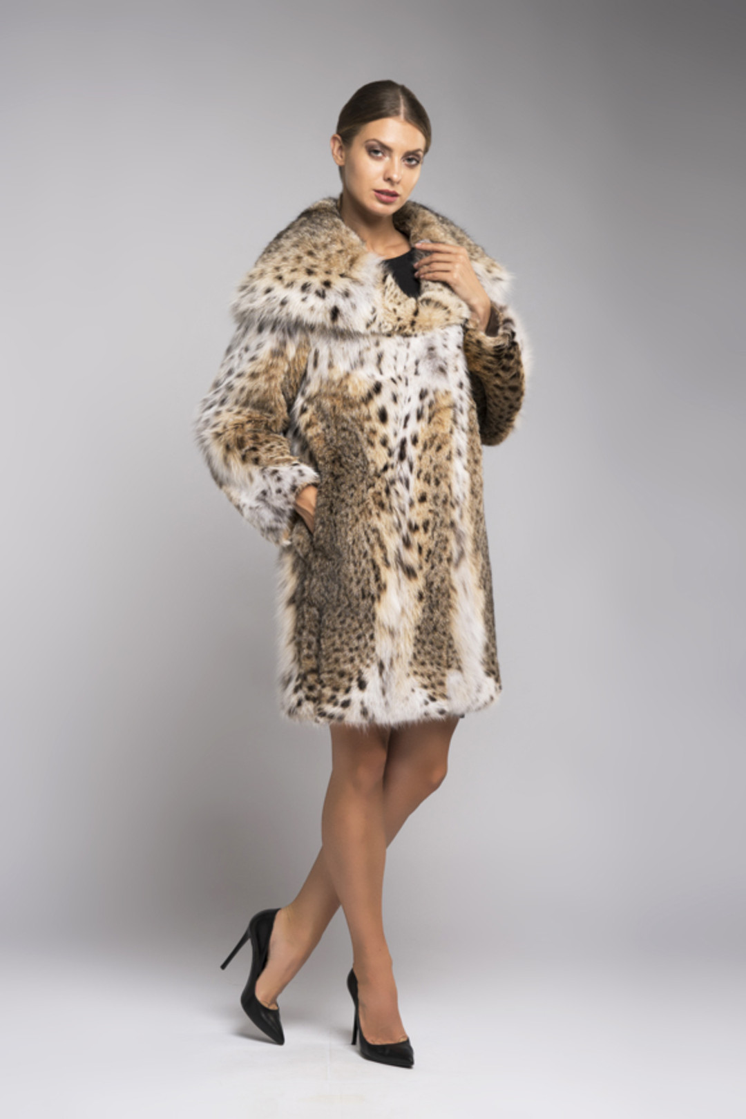 hooded lynx fur coat , knee length on brown haired model with french twist , collarless black blouse and black mini  skirt