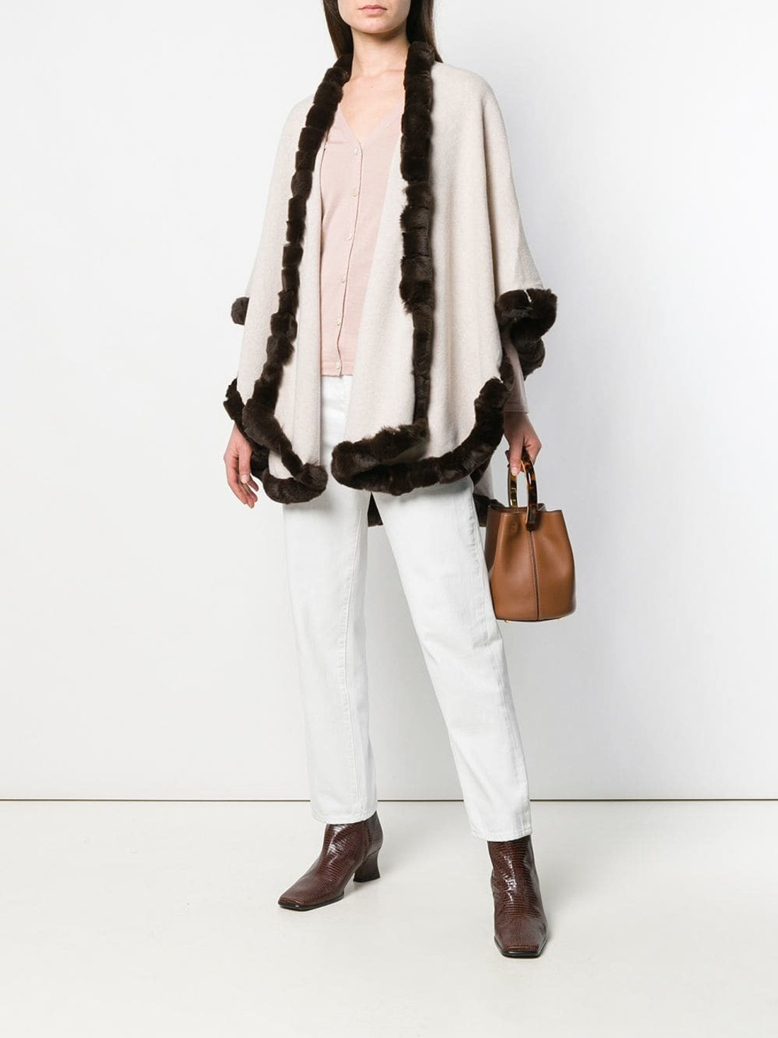 off white cahsmere wool cape with brown rex fur trim o nmodel wearing salmon shirt , white cotton pants , tan leather bag and brown leather boots off white cahsmere wool cape with brown rex fur trim o nmodel wearing salmon shirt , white cotton pants , tan leather bag and brown leather boots