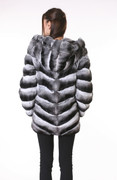 rear view of chinchilla coat with hood on brunette model with skins stitched diagonally , wearing black tight silk pants