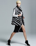 chinchila vest  on model  with black knee length slitted dress and black high heels