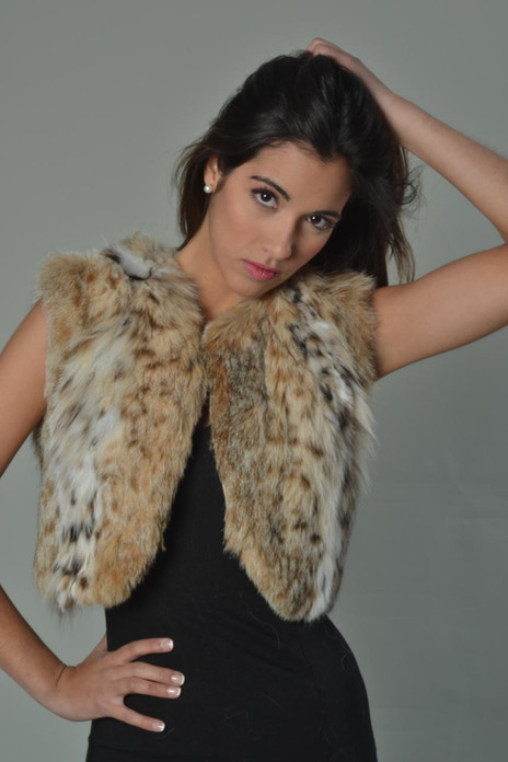 Lynx Fur Bolero cropped above waist , collarless and reverse v opening on bottom , worn by gorgeous brunette model with tight black dress , close up view