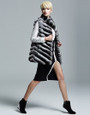 chinchila vest  on model  with black knee length slitted dress and black high heels