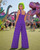 Purple Dinosaur wide leg jumpsuit back view at festival with dinosaur decor
