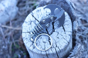 Gravity XS compact stainless steel grappling hook tool shown with cross piece on a wood stump background.