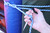 Hand using a stainless steel marlinspike to in tension on a blue rope while tying a knot.