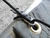 Stainless steel FishBone cord tightener securing paracord to a tarp grommet showing no-knot tensioning setup.