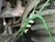 Stainless steel FishBone cord tightener with green paracord wrapped along the spine showing multiple notch tensioning and grip points.