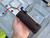 Hand holding a leather firecracker-style paracord dispenser with red 550 cord exiting the top  showing compact size and portability.