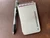Small spiral notebook with a brushed titanium cover labeled “M. Derreberry” placed next to a pen on a textured surface.