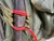 Close-up of a tool handle secured to a green backpack using red cord tightened with a leather toggle slide.