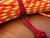 Close-up of a bundle of orange and yellow paracord secured with a red cord and leather toggle slide.