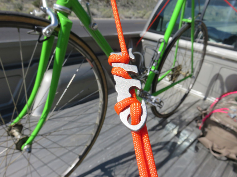 Orange paracord secured to a bicycle frame using a titanium Fishbone tool in a knotless tie-off configuration.