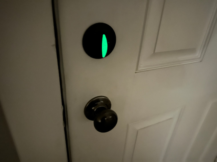 Cat eye stickers applied to a door deadbolt, glowing in low light to indicate lock position.