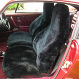 Tailor-made sheepskin seat covers installed on classic car front seats, featuring black natural sheepskin for a luxurious look and enhanced driving comfort.