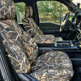 Front seats of a modern truck outfitted with Realtree Waterproof Camo seat covers, featuring a side airbag compatible design and a matching center console cover.
