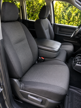 OEM seat covers on front buckets, charcoal textured centers with black bolsters, headrests, and black console armrest.