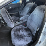 Interior of a vehicle featuring plush, charcoal grey semi-custom sheepskin seat covers on the front bucket seats, with matching sheepskin covers on the steering wheel, center console, and seatbelt for ultimate comfort and a luxurious, unified look.