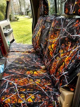 Moon Shine seat covers on truck rear bench in Wildfire camo, white branches over orange and yellow with headrests.