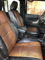 Front bucket seats of a vehicle featuring exotic faux-crocodile skin seat covers in a two-tone Midnight Croc (black) and Java Croc (brown) pattern, offering a bold and luxurious custom look.