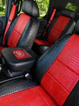 Front bucket seats in a Cadillac featuring black and red exotic seat covers with a textured crocodile finish, complemented by a matching custom center console cover for a high-end, personalized look.