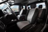 Car interior with Cordura seat covers as a man places work tools on the front seat through the open door.