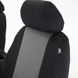 Close-up of black and grey seat covers showing a custom headrest fit and side airbag safety label.