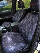 Front truck seats protected by Kryptek® "Typhon" camo seat covers, featuring a sleek dark-grey scale pattern and durable, custom-tailored construction.
