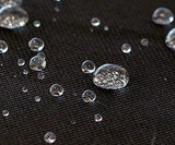 Close-up of water-resistant fabric on Atomic Pet Seat Covers, showing water beads on the durable black surface.