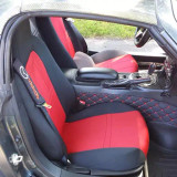 Sporty red and black neoprene seat covers installed in a convertible, featuring a custom logo on the headrest area and complementing the vehicle's performance interior.