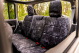Rear bench seat of a vehicle protected with custom-fit Kryptek Typhon camo waterproof seat covers.