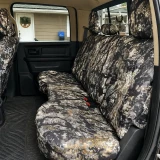 Rear bench seat of a pickup truck fully outfitted with custom Kryptek® Waterproof Camo seat covers in the earthy "Highlander" pattern.