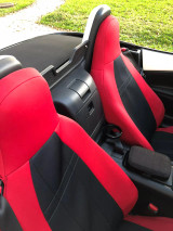 Sporty red and black neoprene seat covers in a convertible, designed to withstand UV exposure and moisture while enhancing the car's interior style.