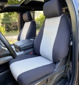 Neoprene seat covers on Ford truck front buckets, charcoal bolsters with light gray grid-stitched centers and headrest wraps.