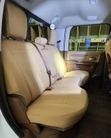 Neoprene seat covers on truck rear bench in solid tan, snug custom fit over three headrests, backrest, and cushion.