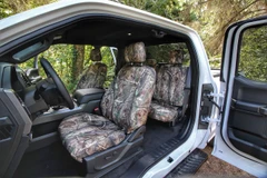 Realtree Waterproof Camo Seat Covers installed in a truck interior, camo pattern on front and rear seats for durable protection.